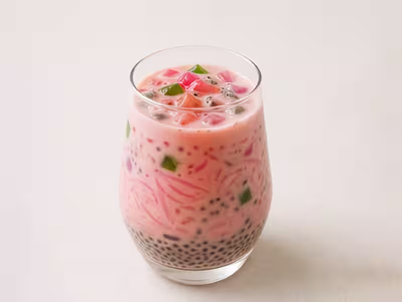 A tall glass of faluda with rose syrup and jelly layers