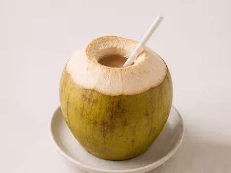 An orange king coconut with a straw