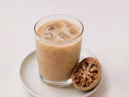 A glass of wood apple juice, pale brown and thick
